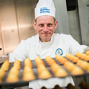 Claude dans l'atelier derrière les moules remplis de madeleines